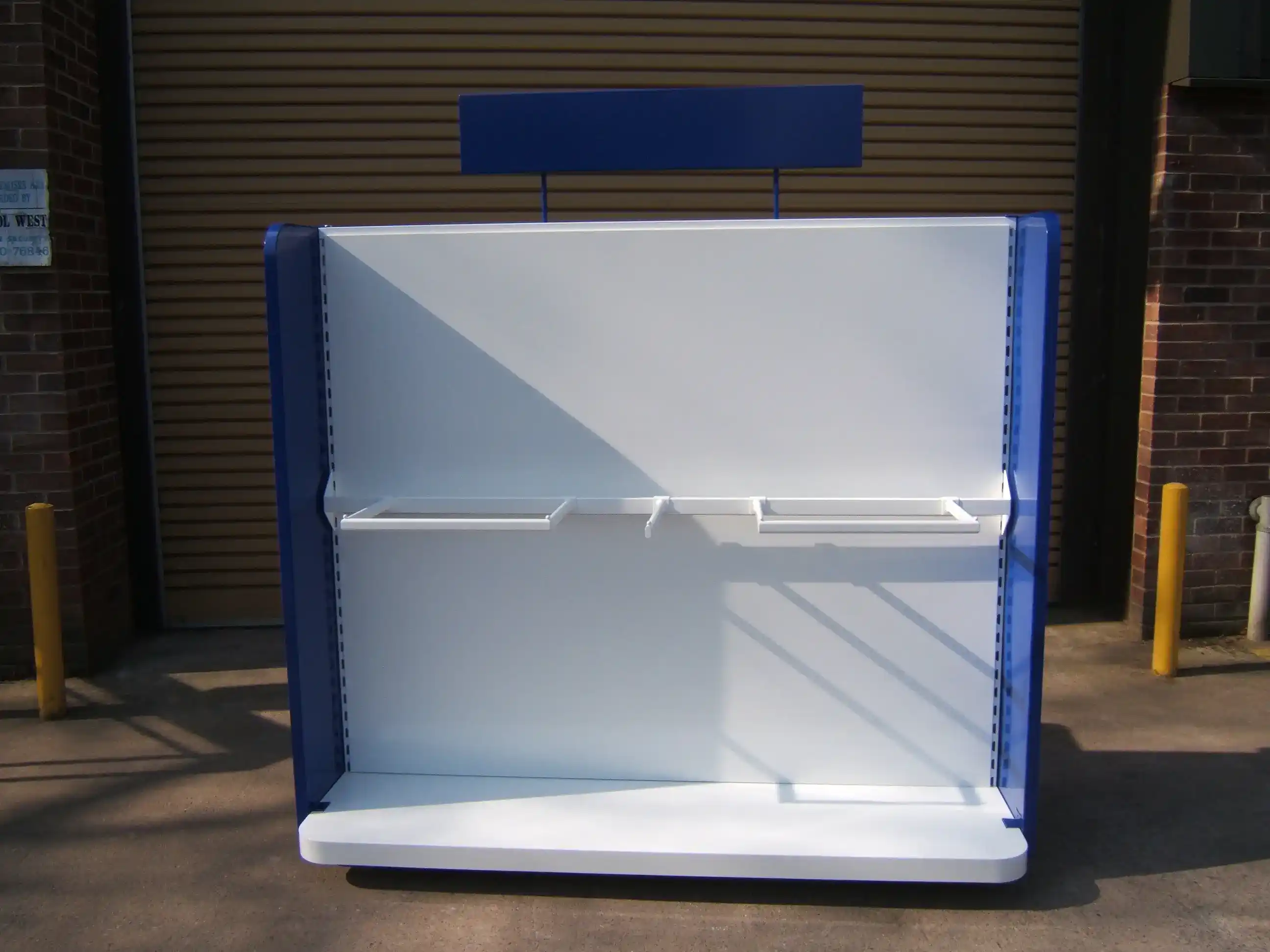Freestanding Retail Merchandise Display manufactured by Techrail Powder-coated shop-floor display fixture with shelves, side panels and an overhead header board.