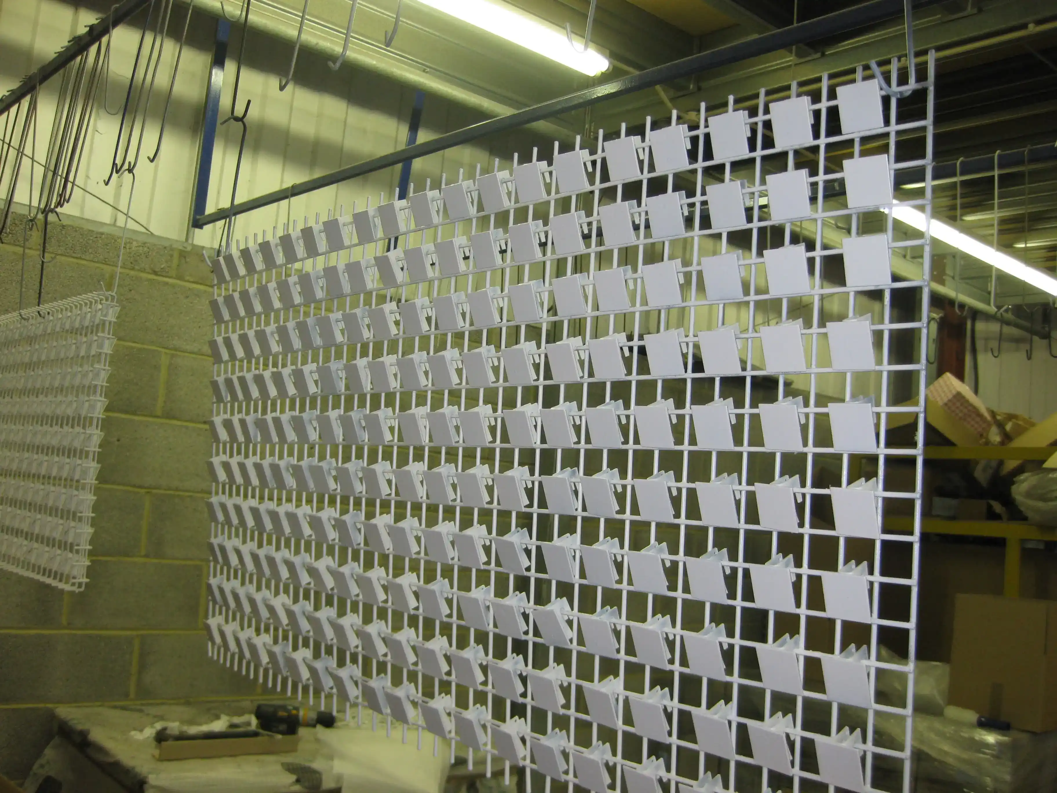 Powder-Coated Production Parts on Conveyor manufactured by Techrail Batch-manufactured metal components suspended on the powder coating conveyor line.