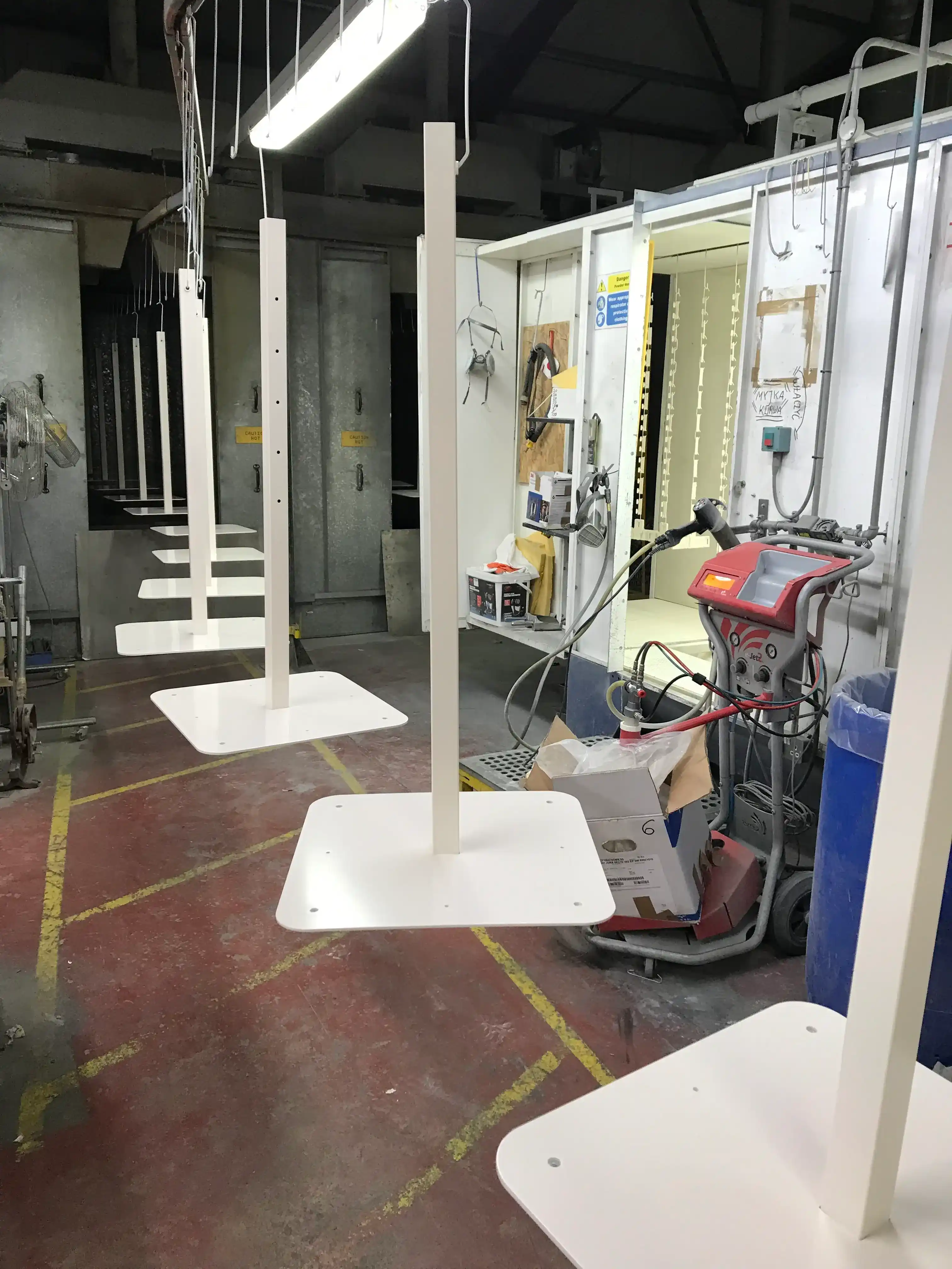 Powder-Coated Retail Display Stands manufactured by Techrail Fabricated floor-standing display bases receiving a durable white powder-coated finish.